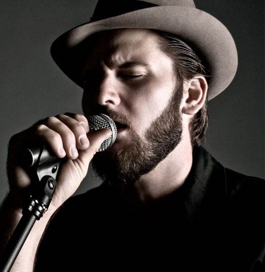 Cantante con sombrero grabando su voz con un micrófono